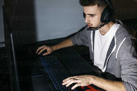 Young Man Sitting At His Pc Playing Computer Games Stock Photo
