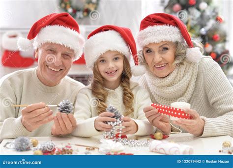 Grandparents With Grandchild Preparing For Christmas Together Stock