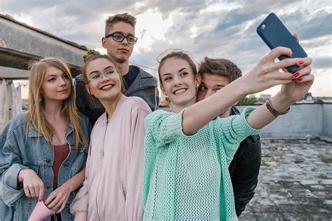 Group Of A Teenage Friends Having Fun And Taking Group Selfie On The Roof Of The Building By