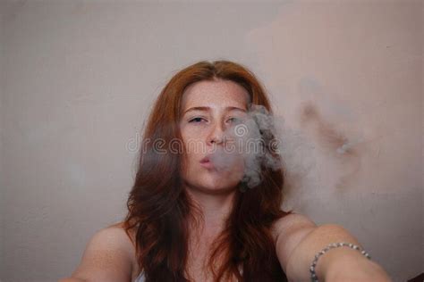 A Young Red Haired Girl In A White T Shirt Smokes And Lets Smoke Out Of