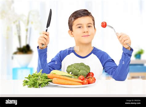 Young Boy Eating Healthy Meal Seated At A Table Stock Photo Alamy