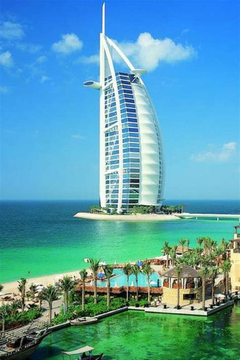 The Burj Hotel In Dubai Is Surrounded By Palm Trees And Blue Water With