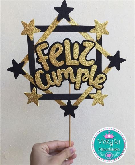A Cake Topper With The Words Feliz Cumple In Gold And Black