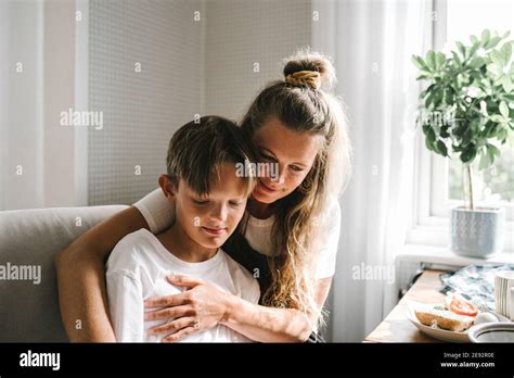 Smiling Mother Embracing Son At Home Stock Photo Alamy