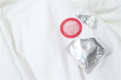premium photo condom ready to use in female hand give condom safe sex concept on the bed