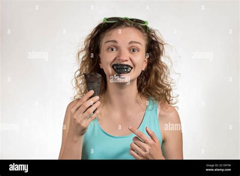 Beautiful Cheerful Girl With Curly Hair Eats Black Ice Cream In A