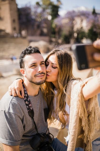 Free Photo Woman Kissing Her Boyfriend Taking Selfie On Smartphone