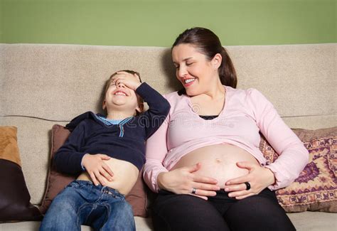 Pregnant Mother And Son Laughing And Comparing Bellies Stock Photo