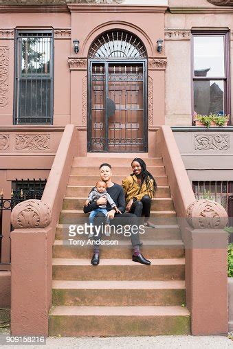Young Father Mother And Infant Daughter On Stoop In Their City