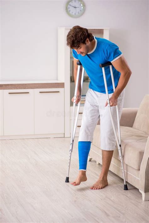 The Leg Injured Young Man With Crutches At Home Stock Photo Image Of