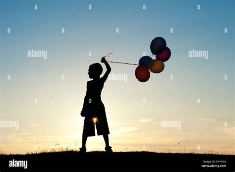 Silhouette Of A Young Boy Holding Balloons At Sunset Stock Photo Alamy