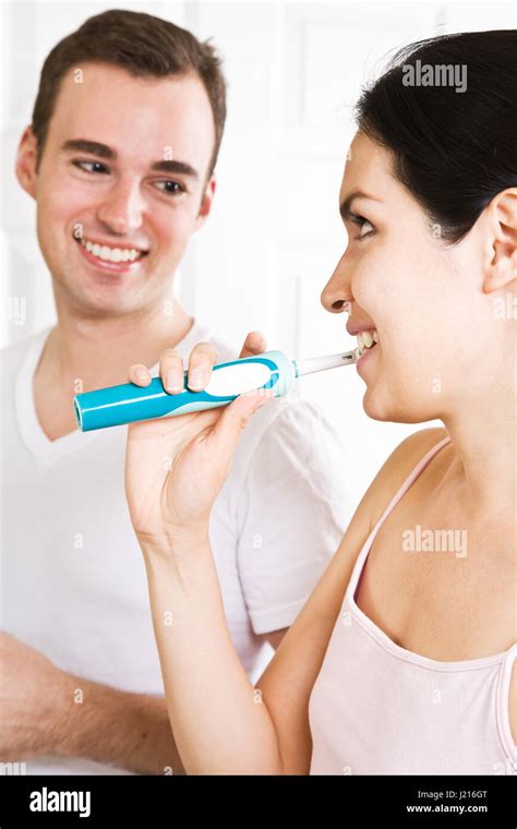 A Beautiful Interracial Couple In The Bathroom Brushing Teeth Stock