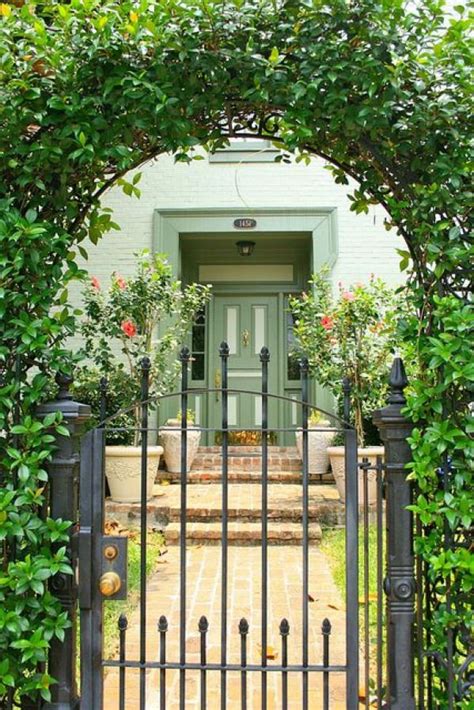 An Iron Gate With A Green Door Surrounded By Greenery