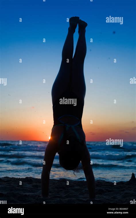 Young Girls Silhouette Handstand On The Beach At Sunset Stock Photo