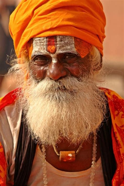 An Old Man With A White Beard And Orange Turban Is Looking At The Camera