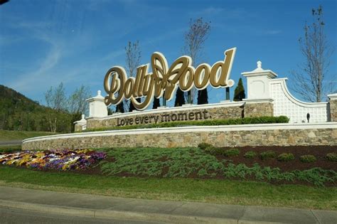The Entrance Sign To Dollywood Is Surrounded By Flowers And Bushes In