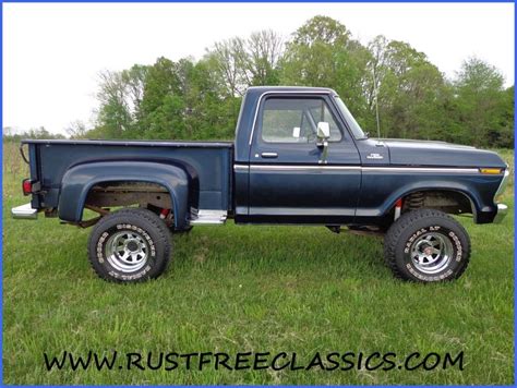 A Blue Pick Up Truck Parked On Top Of A Lush Green Field