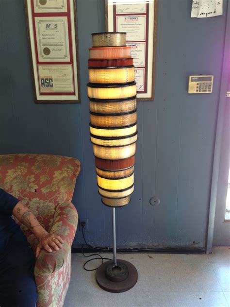 A Tall Wooden Lamp Sitting On Top Of A Floor Next To A Chair In A