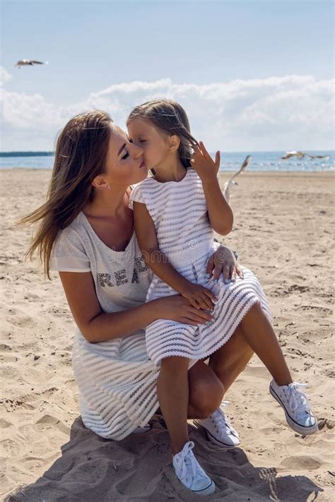 Mother Holding The Daughter Sitting On Her Knees On The Beach Stock