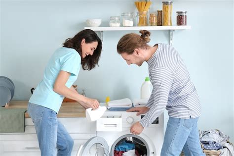 Jovem Casal Feliz Lavando Roupa Em Casa Foto Premium