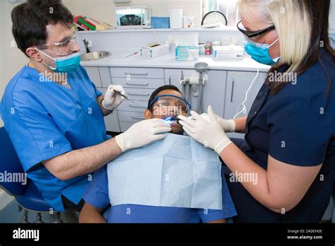 Dentist And Dental Nurse Carrying Out Dental Treatment On A Patient