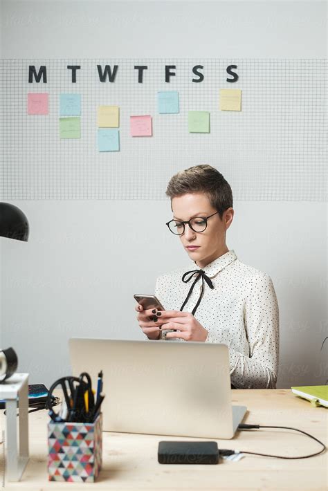 Stylish Woman With Glasses Looking At The Phone In The Office By