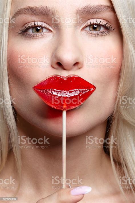 Portrait Of Blonde Woman Kissing Candy Red Female Lips Shape Lollipop Sweet Tooth Concept Stock
