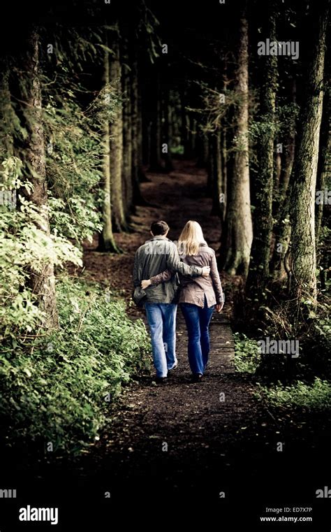 A Couple Walking Through The Woods Arm In Arm Stock Photo Alamy