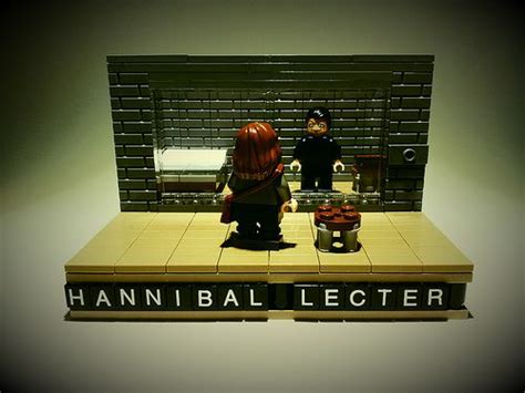 Two Lego Figures Standing On Top Of A Table Next To A Sign That Reads
