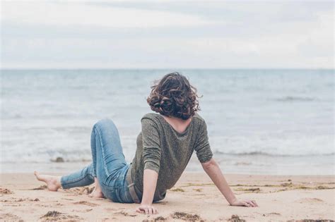 Young Woman Sitting On The Beach Looking At The Sea Stock Photo