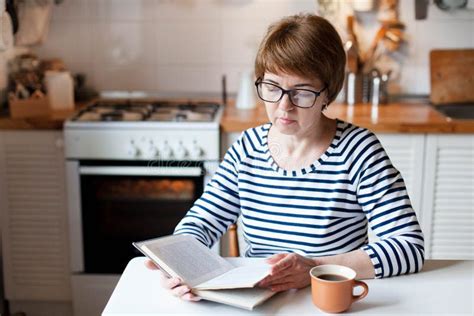 Reading Book At Home Middle Aged Woman Drinking Coffee In Cozy Kitchen