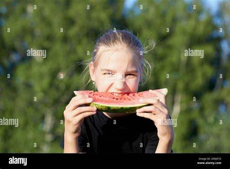 Pretty Young Girl Eating Red Juicy Watermelon In Green Park Background