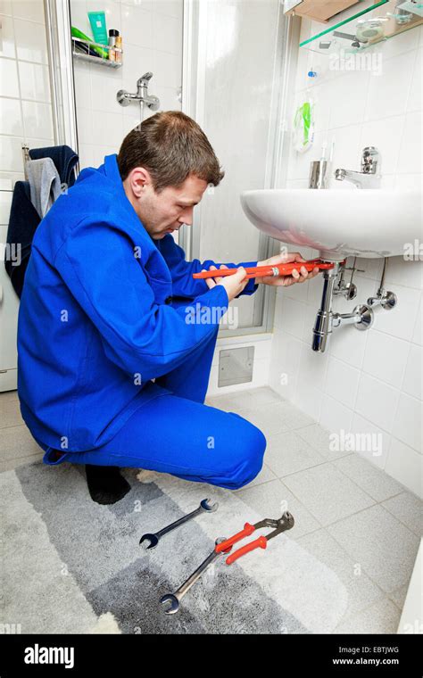 Plumber Repairing A Sink In Bathroom Stock Photo Alamy