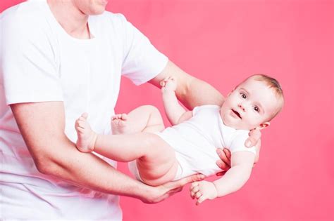 El Papá Con Una Camiseta Blanca Balancea A Un Lindo Bebé En Las Manos