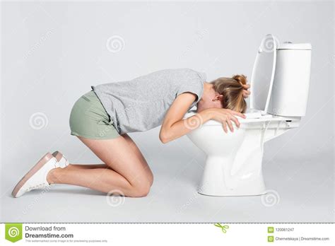 Mujer Que Vomita En Taza Del Inodoro En Fondo Gris Imagen De Archivo