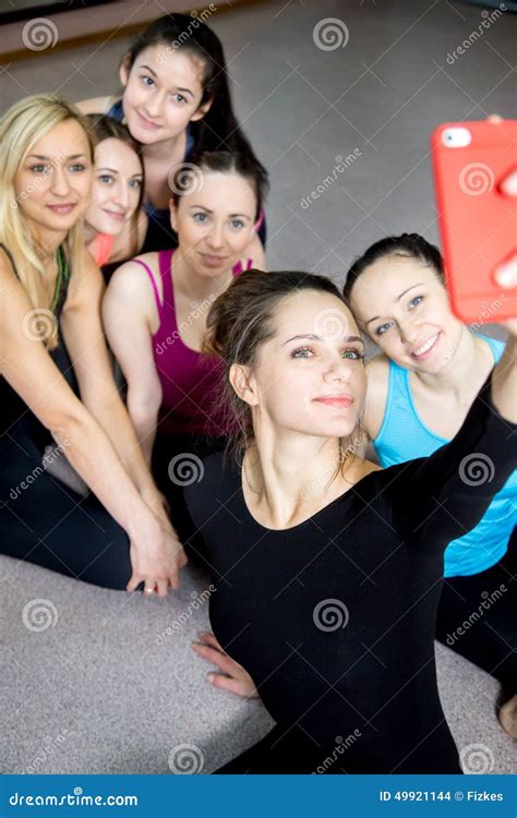 group of beautiful sporty girls posing for selfie self portrait with smart phone in sports gym