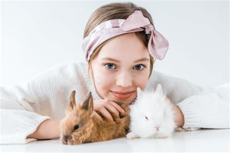 Adorable Little Girl Playing With Rabbits And Smiling At Camera Stock