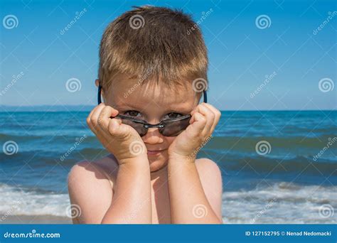 A Beautiful Little Boy Posing On A Beach By The Sea With Sunglasses