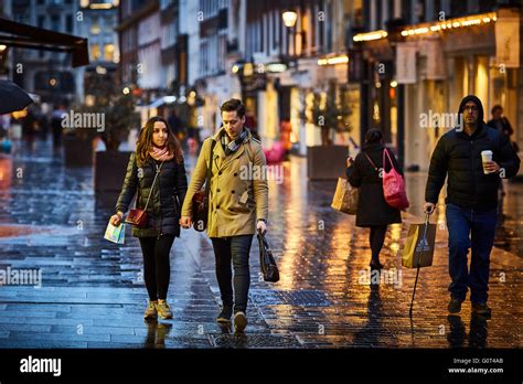 London Street At Night And Wet Raining Evening Shopper Walking Stock