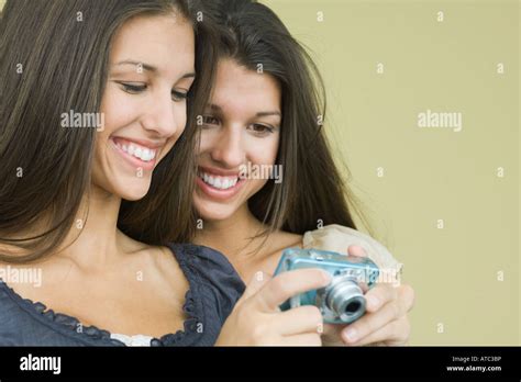 Teenage Twin Sisters Looking At Digital Camera Together Both Smiling