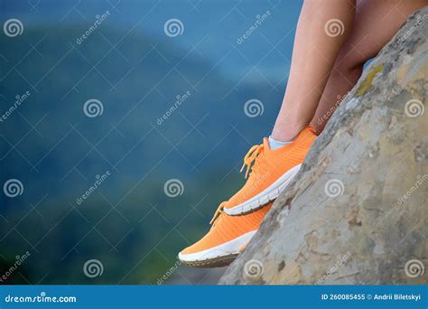 Closeup Of Woman Hiker Legs Seated Alone On Rocky Mountain Cliff