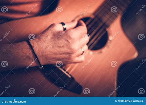 Male Musician Playing On Acoustic Guitar While Sitting Down Stock Image
