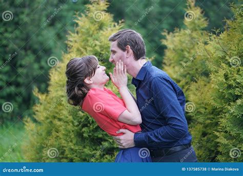 Pretty Caucasian Love Couple Walking In The Green Summer Park Having Smiles Kisses And Hugs