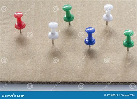Multi Colored Push Pins On White Cardboard Paper Texture Background