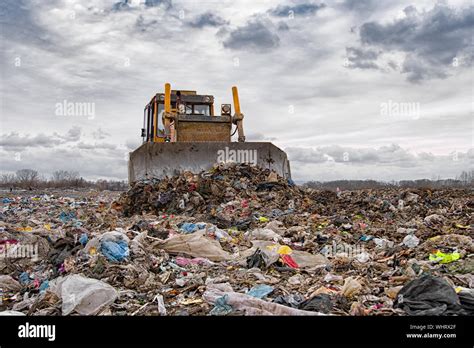Bulldozer Working On Landfill With Birds In The Sky Sunset Stock Photo