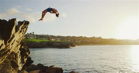 Young Man Doing Backflip Cliff Jumping Into Ocean At Sunset Stock Video Footage Dissolve