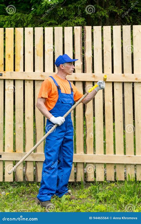 Handyman In Blue Working Uniform Checks The Condition Of Paint Roller