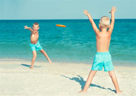 Brothers Play With Frisbee On The Beach Summer Holidays Stock Image
