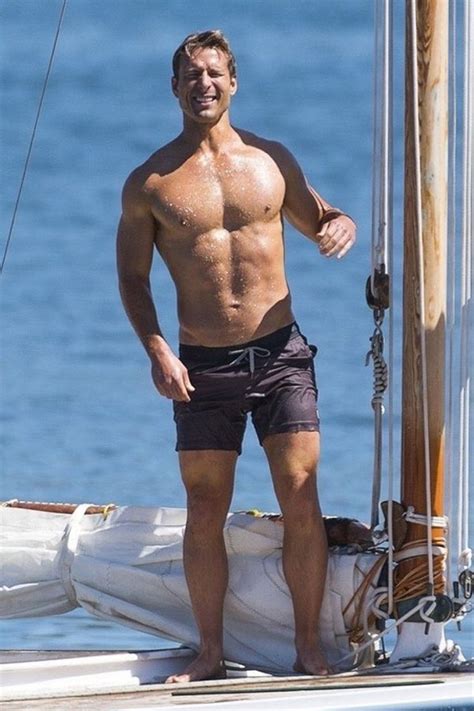 A Shirtless Man Standing On The Deck Of A Sailboat
