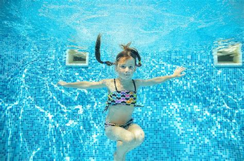 Девочка прыгает и плавает в бассейне под водой счастливый активный